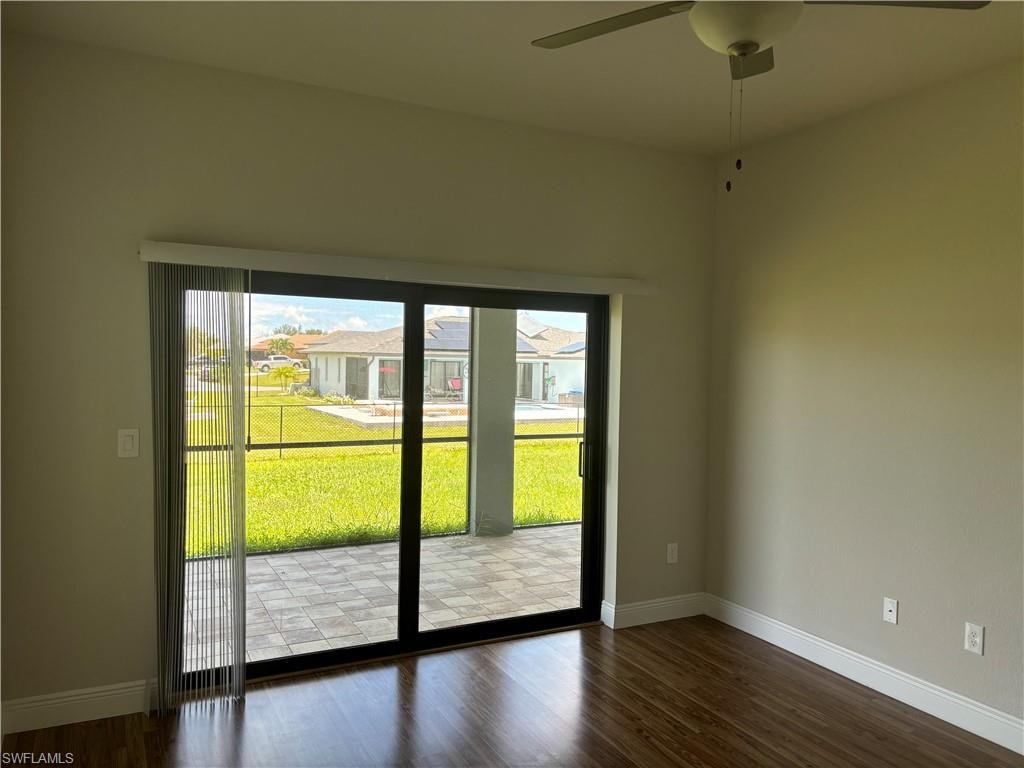 Empty room featuring ceiling fan and dark hardwood / wood-style flooring