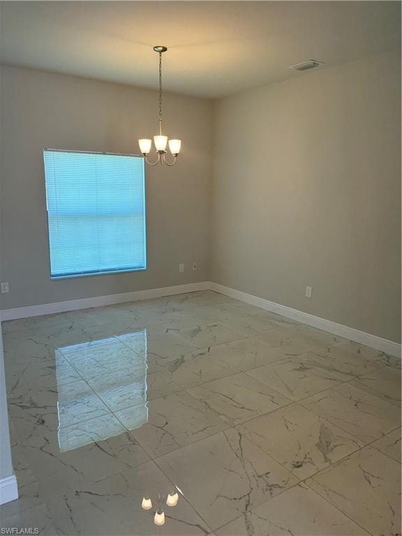 Spare room with a notable chandelier and tile flooring