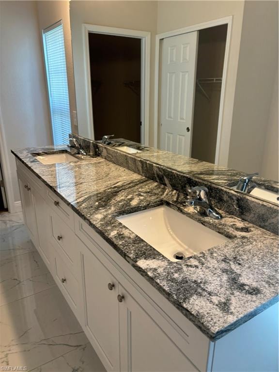 Bathroom with vanity with extensive cabinet space, tile flooring, and dual sinks