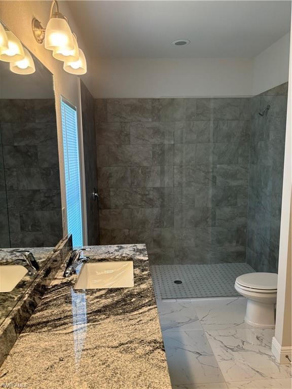 Bathroom with a tile shower, tile flooring, vanity, and toilet