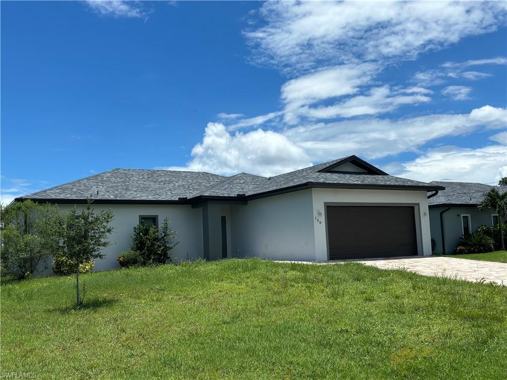 View of front of property with a front yard and a garage