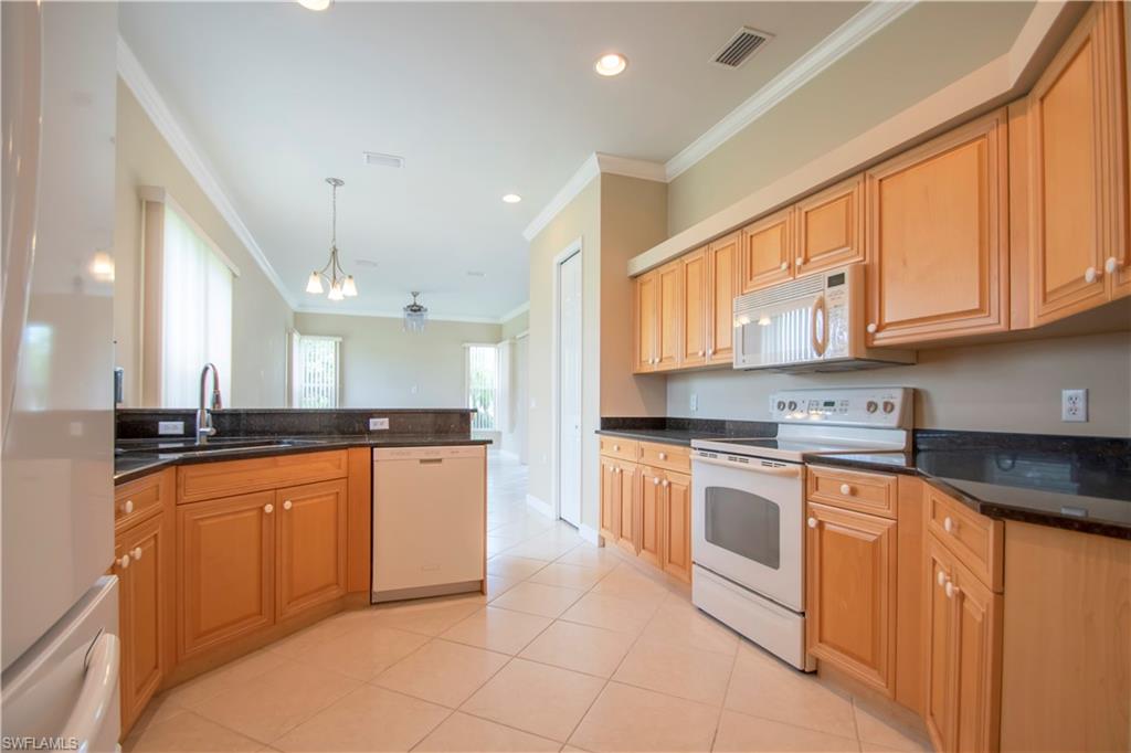 Kitchen with white appliances, sink, pendant lighting, light tile patterned floors, and ornamental molding