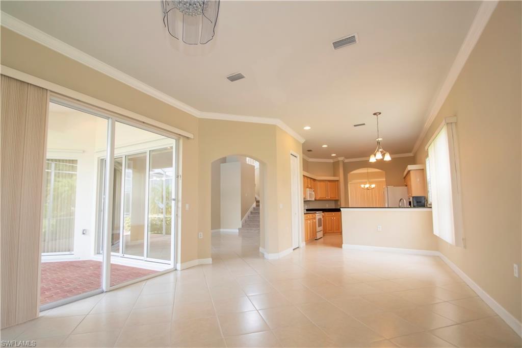 Unfurnished living room with light tile patterned flooring, ornamental molding, and a notable chandelier