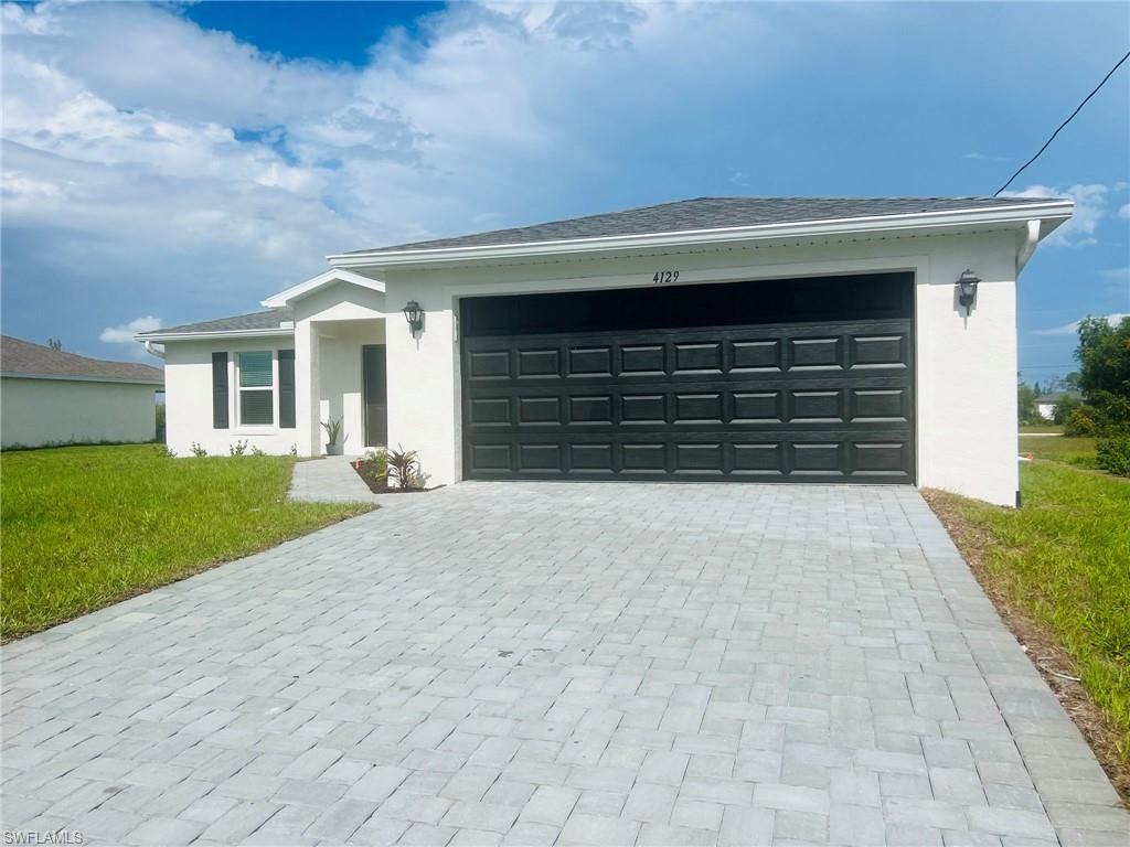 Contemporary stucco exterior featuring a dark paneled garage door, a paver driveway, a covered entry, and black window shutters