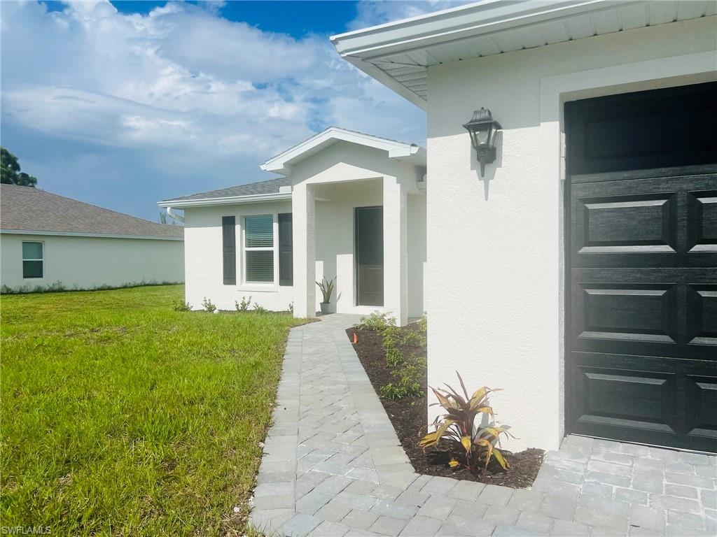 Contemporary exterior featuring a white stucco finish, dark paneled garage door, and a paved walkway
