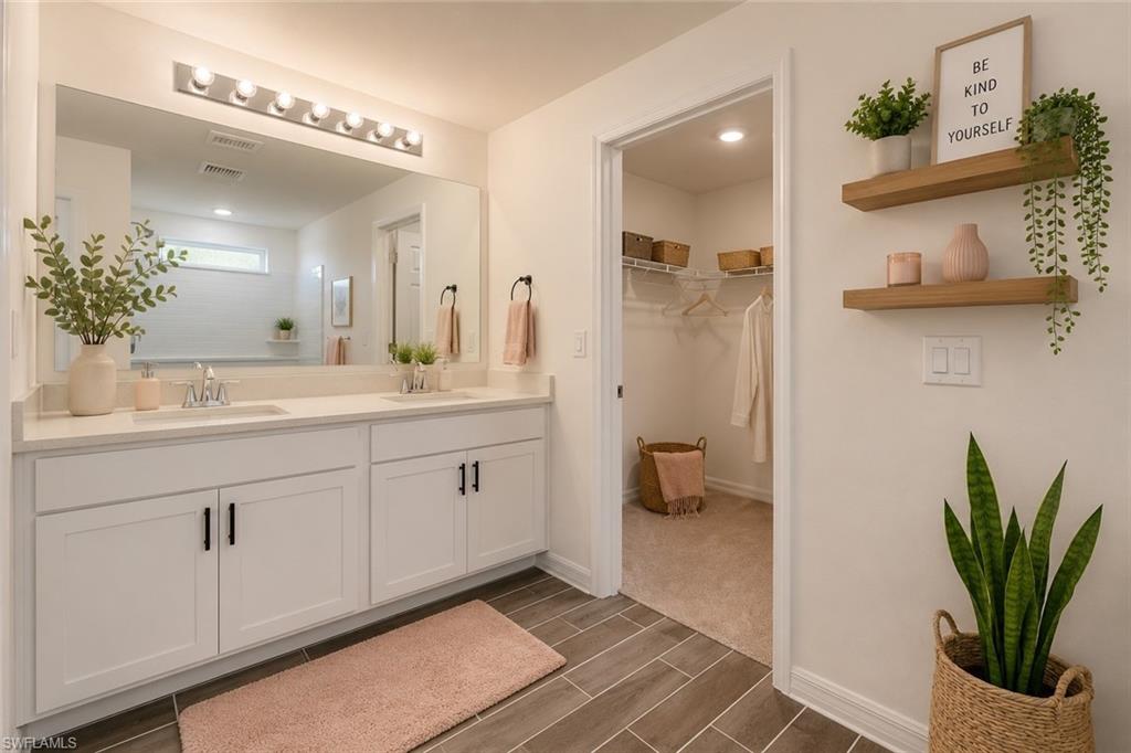 Bathroom featuring a dual vanity with white cabinetry, quartz countertops, and matte black hardware