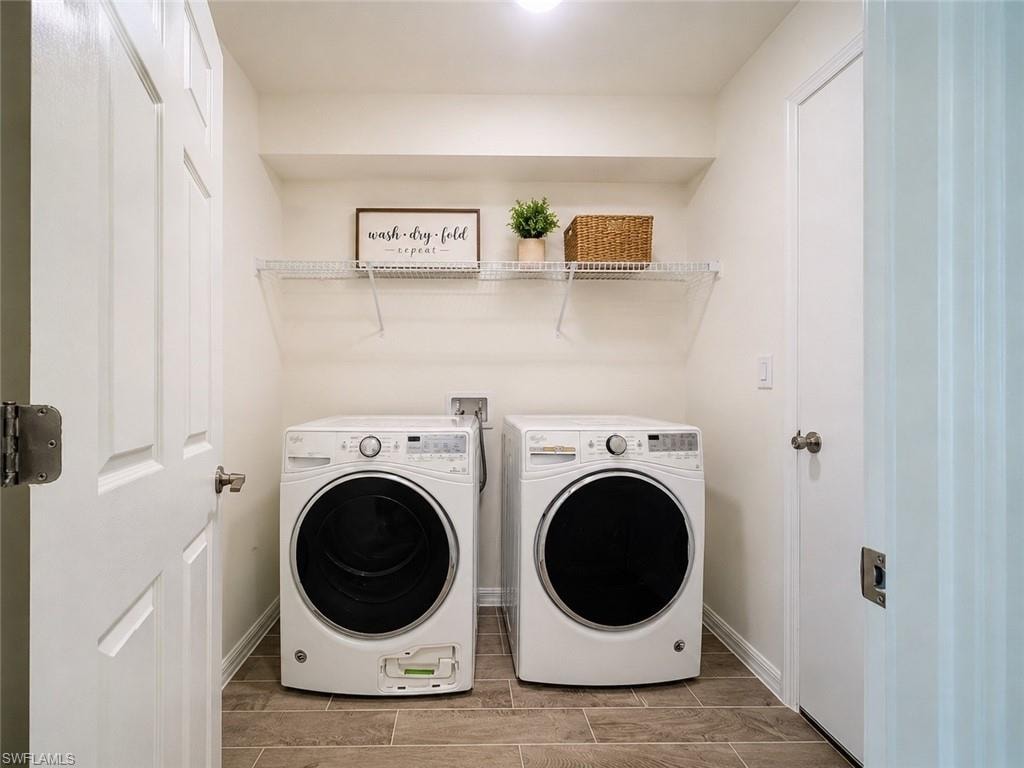 Dedicated laundry area featuring front-loading washer and dryer units, wire shelving, and wood-finish flooring