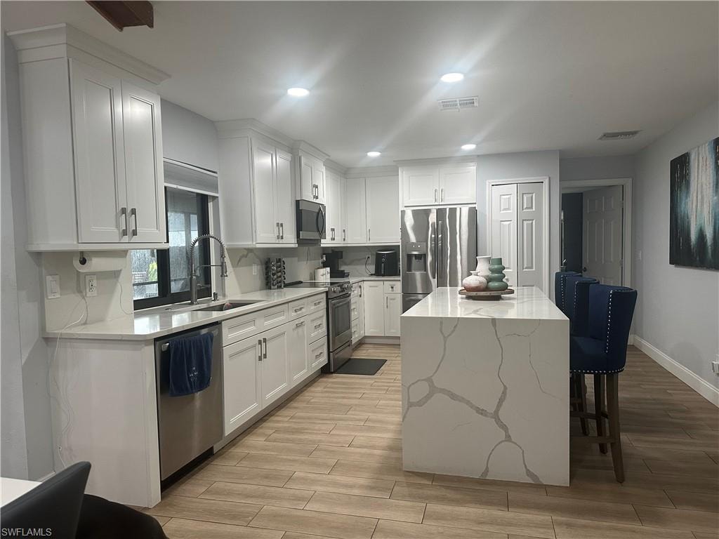 Modern kitchen featuring white shaker cabinetry and a large waterfall island with veined stone
