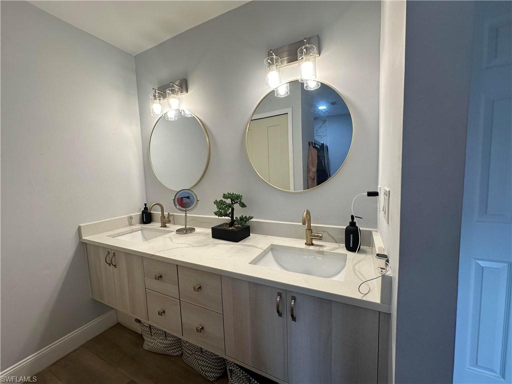 Dual vanity with light wood-finish cabinetry, integrated sinks, and a light-toned countertop
