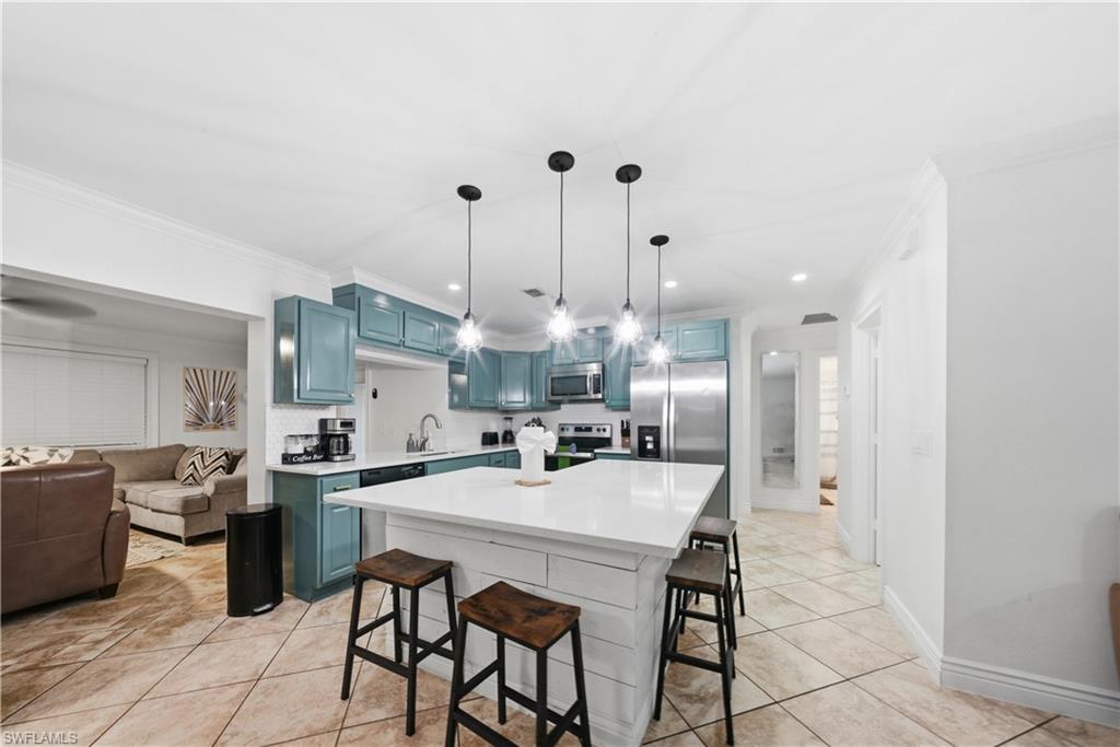 Open-concept kitchen featuring an island with seating, a white countertop, and four pendant lights