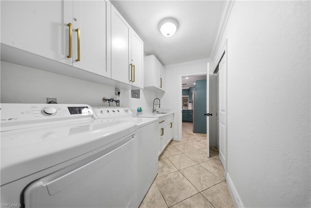 Laundry area featuring white cabinetry with gold-tone hardware, a built-in sink, and tile flooring