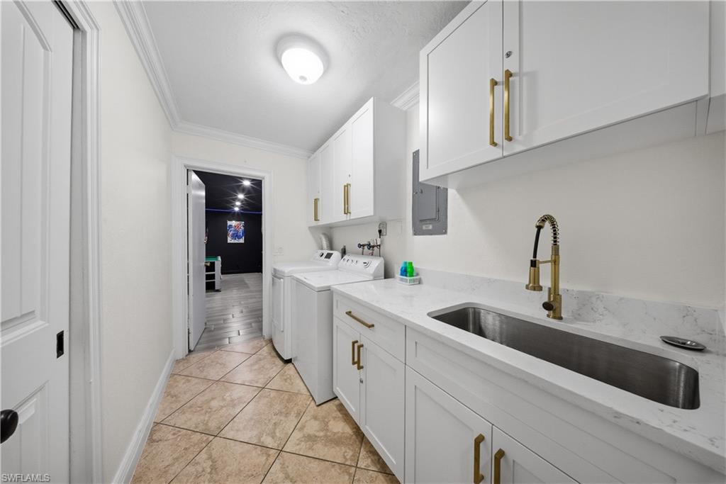 Dedicated utility space featuring white cabinetry with gold-toned hardware, a deep rectangular stainless steel sink, and a gold-toned gooseneck faucet