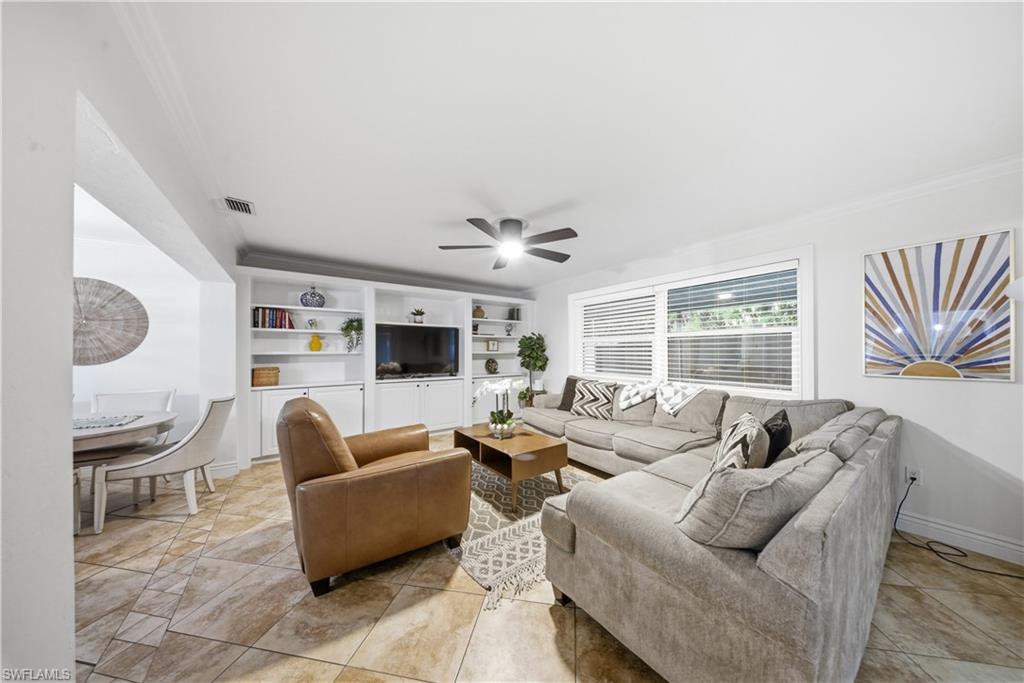 Living area featuring tile flooring, a ceiling fan, and a large window with horizontal blinds