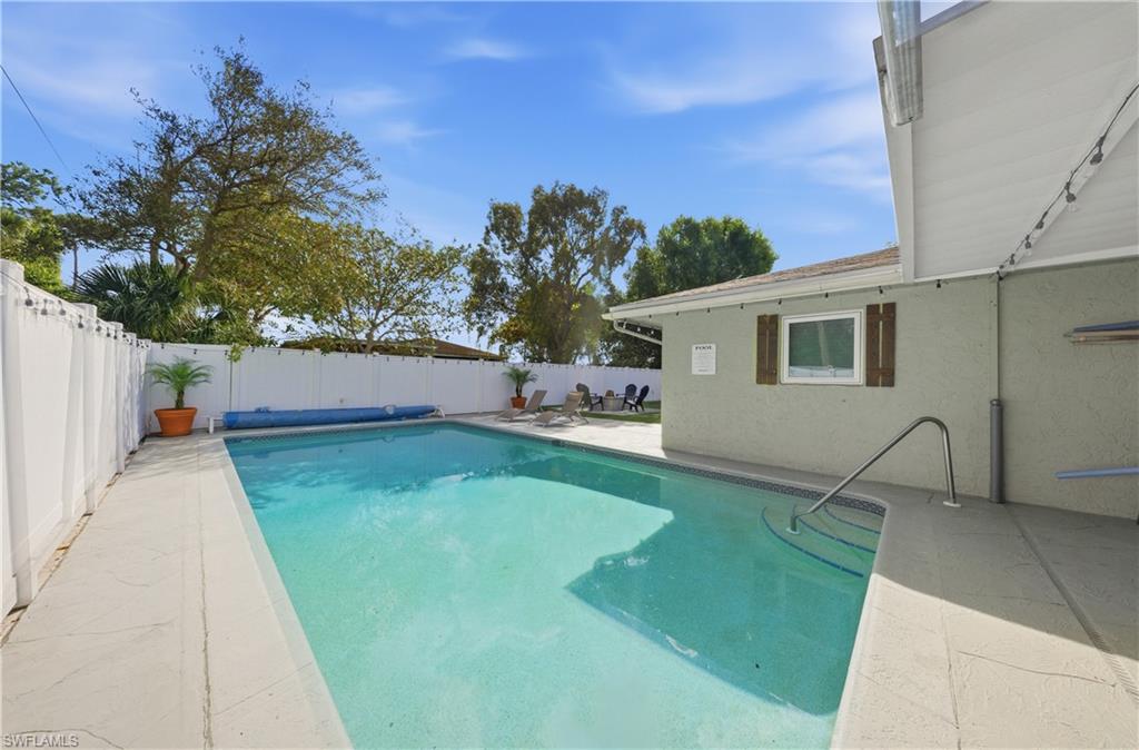 Outdoor swimming pool with integrated steps and a metal handrail, surrounded by concrete decking