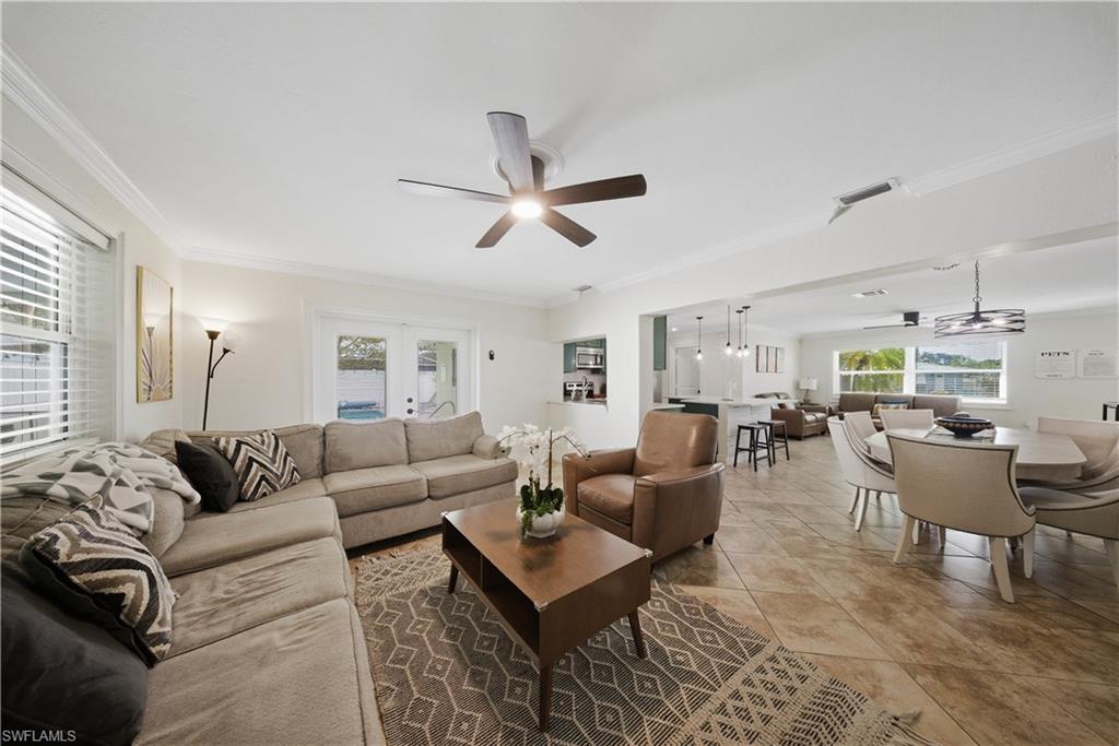 Open-concept living area featuring tile flooring, crown molding, and recessed lighting
