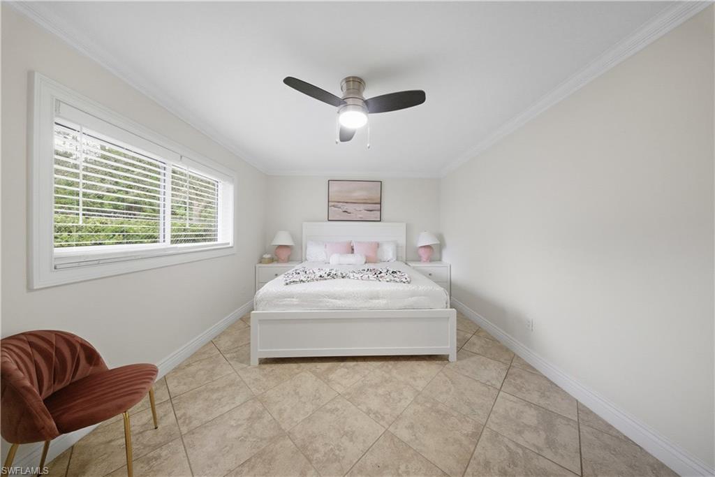 Spacious room featuring neutral-toned tile flooring, white baseboards, and crown molding