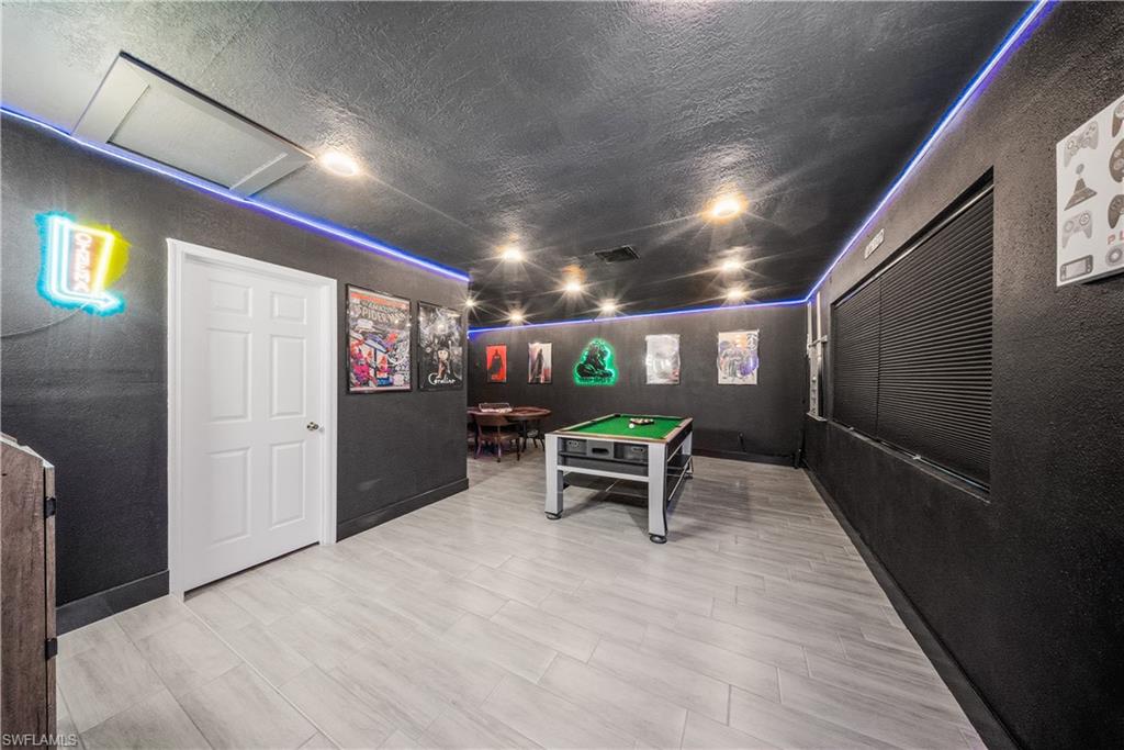 Recreation room featuring wood-finish flooring, recessed lighting, and a neutral-toned door