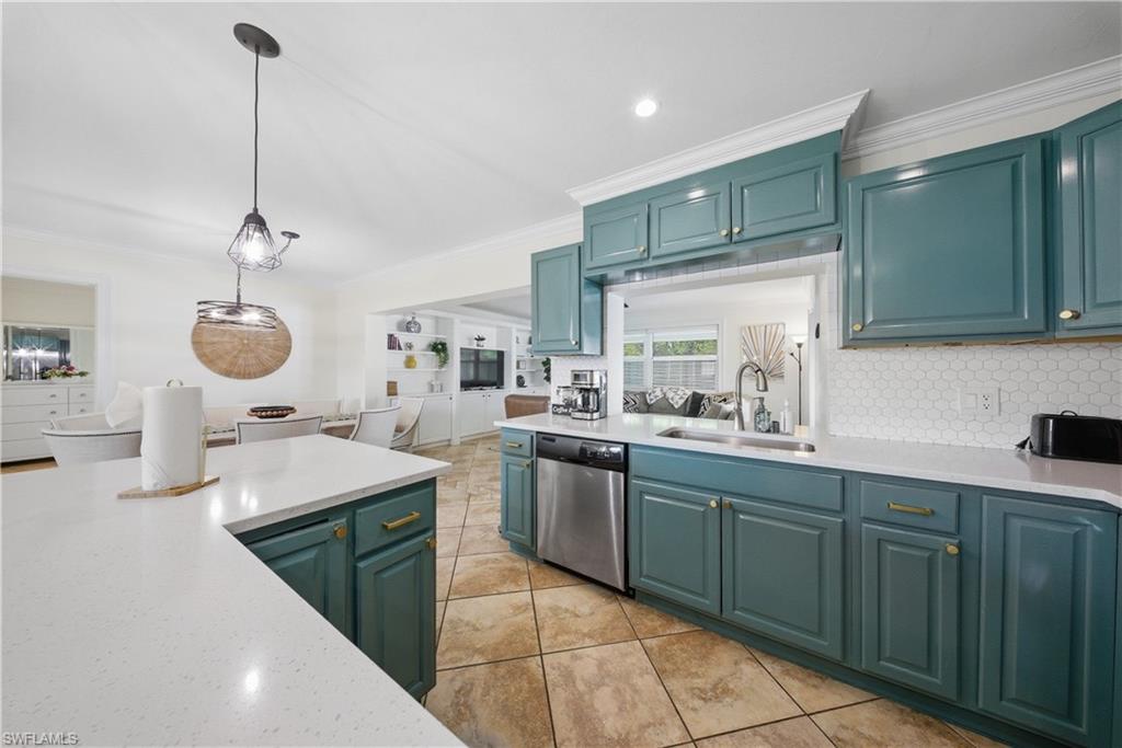 Kitchen featuring teal cabinetry, stone-finish countertops, stainless steel appliances, and a hexagonal tile backsplash