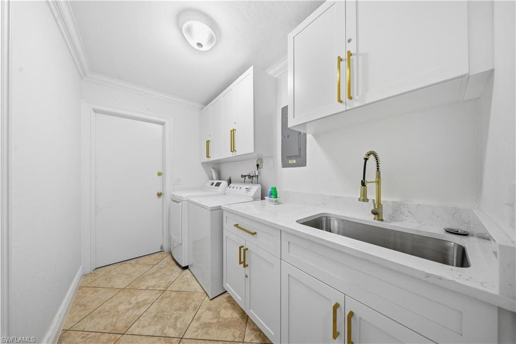 Utility room featuring white cabinetry, a built-in stainless steel sink with gold-finish faucet, white countertops, and neutral-toned tile flooring