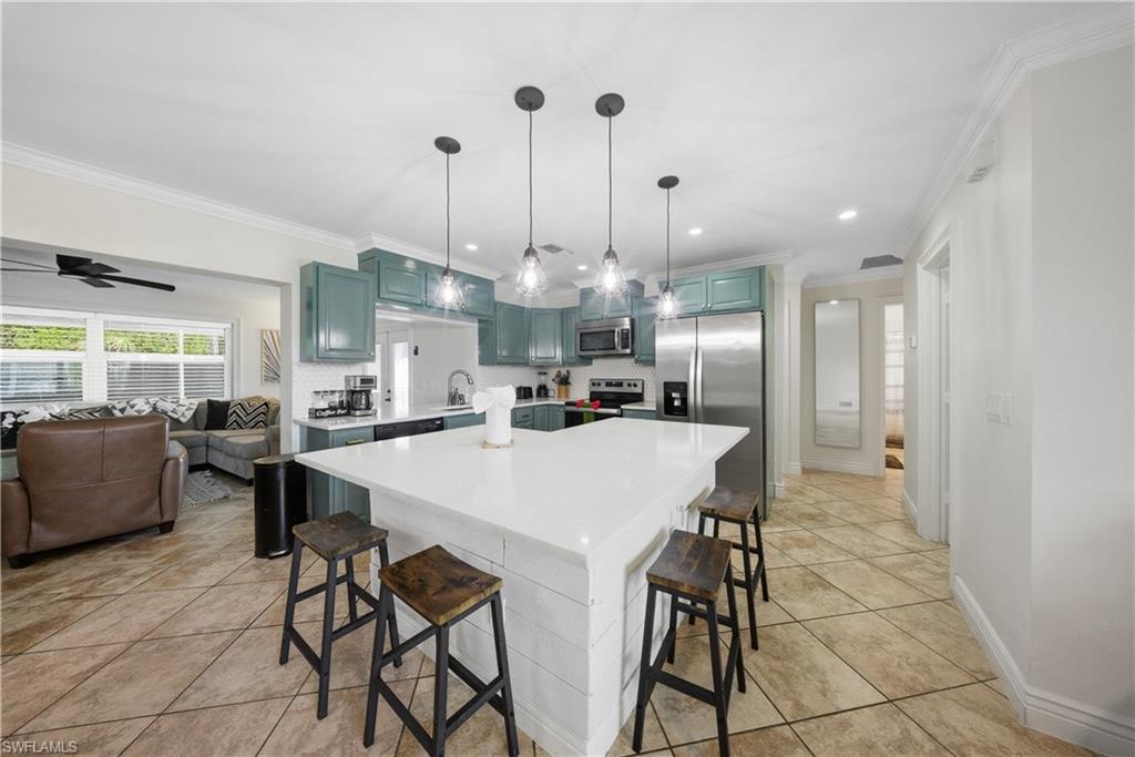Kitchen featuring a large island with white shiplap base, light countertops, and pendant lighting
