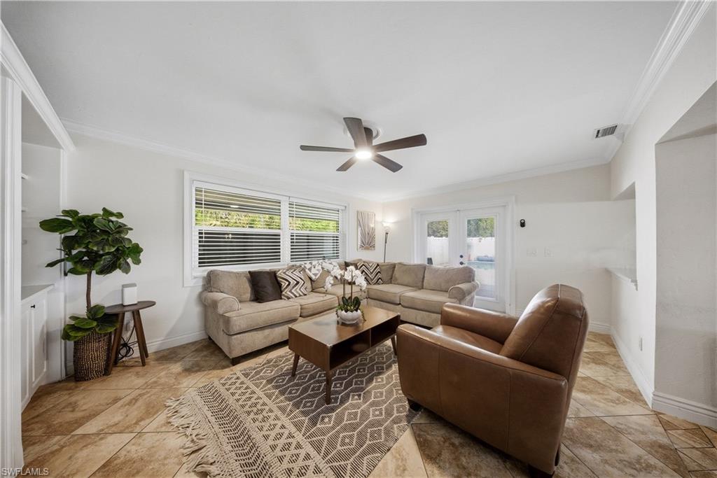 Living room featuring diagonal tile flooring, white crown molding, and a ceiling fan with integrated lighting