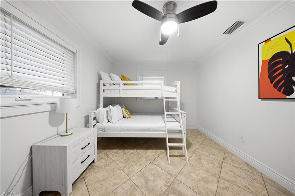 Room featuring light-colored tile flooring, white walls, and crown molding