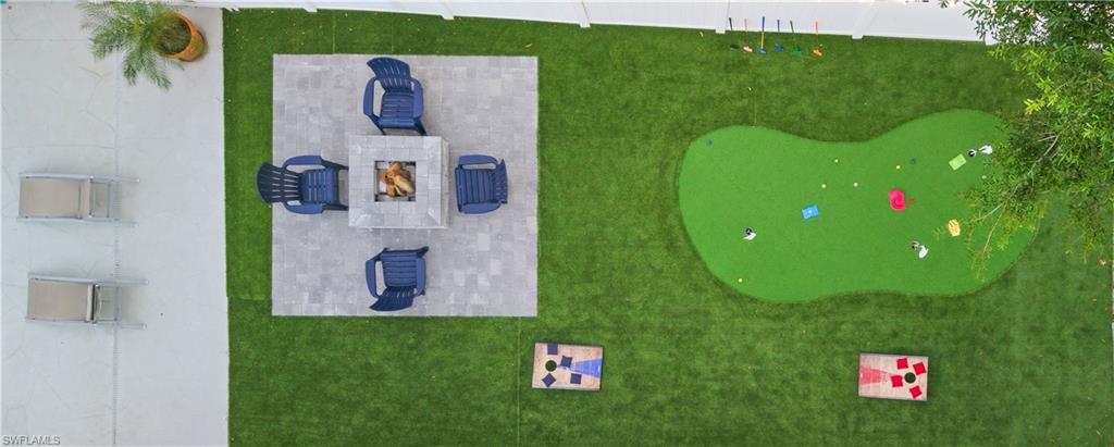Expansive outdoor space featuring a putting green, paver patio, and stone fire pit
