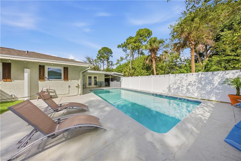 Outdoor swimming pool with a white privacy fence and a surrounding concrete patio