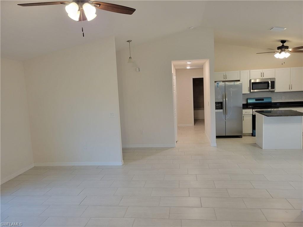 Kitchen featuring lofted ceiling, ceiling fan, stainless steel appliances, and white cabinetry