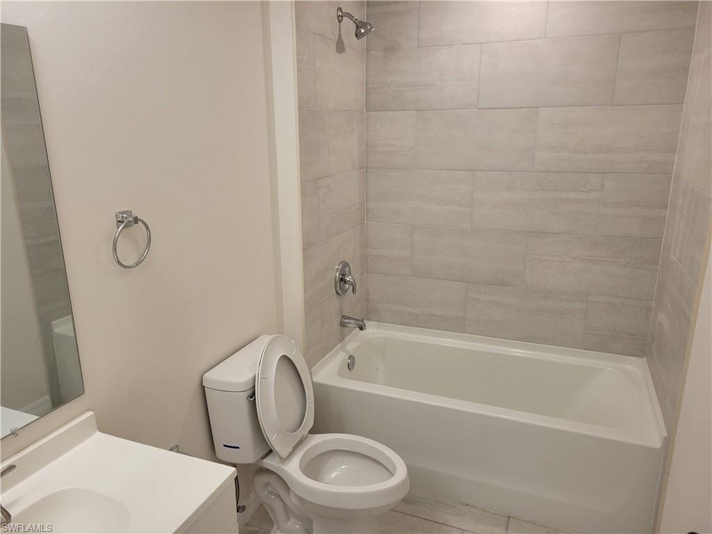 Full bathroom featuring tiled shower / bath, vanity, and toilet