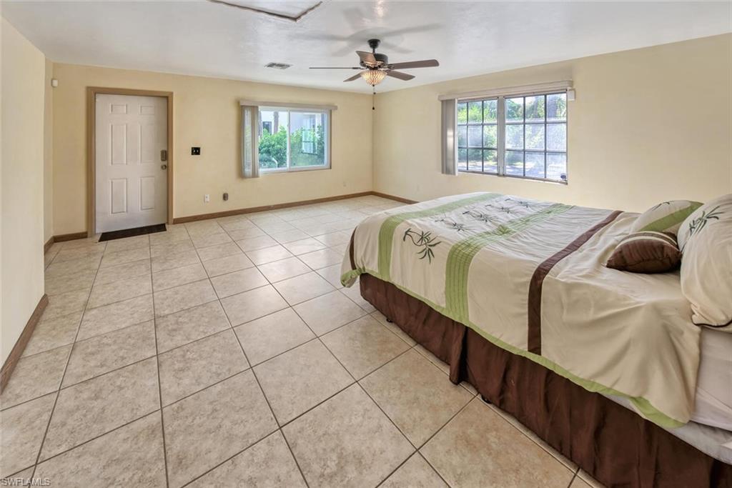Bedroom featuring light tile patterned flooring, ceiling fan, and multiple windows