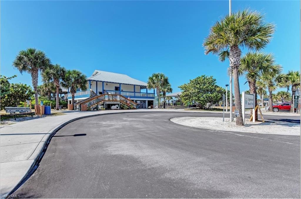Elevated coastal-style structure featuring a white metal roof, blue exterior trim, and a wrap-around porch