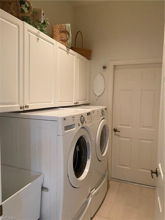 Laundry room with washing machine and dryer, cabinet space, a sink, and light tile patterned floors