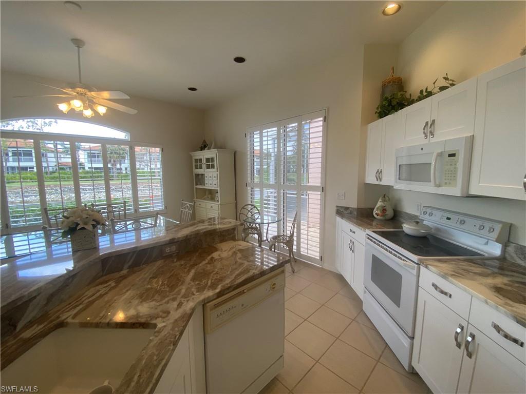 Kitchen featuring light stone countertops, light tile patterned flooring, a healthy amount of sunlight,