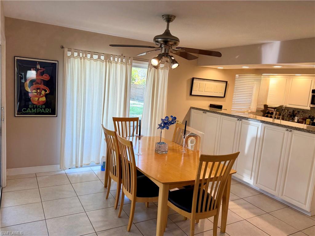 Dining area featuring tile flooring, a ceiling fan with integrated lighting, and a sliding glass door providing exterior access