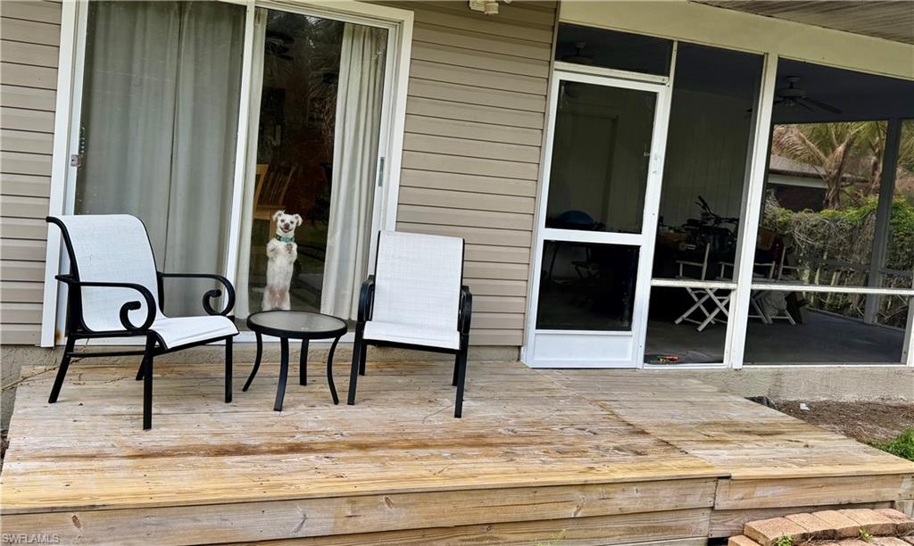 Exterior wood deck featuring vinyl siding, a sliding glass door, and an attached screened-in porch with a ceiling fan