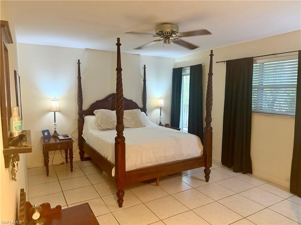 Spacious room featuring neutral wall tones, large format tile flooring, a ceiling fan, a window with blinds, and a glass-paned door
