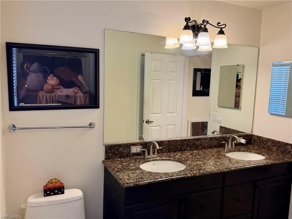 Double vanity featuring a speckled countertop, undermount sinks, and dark cabinetry