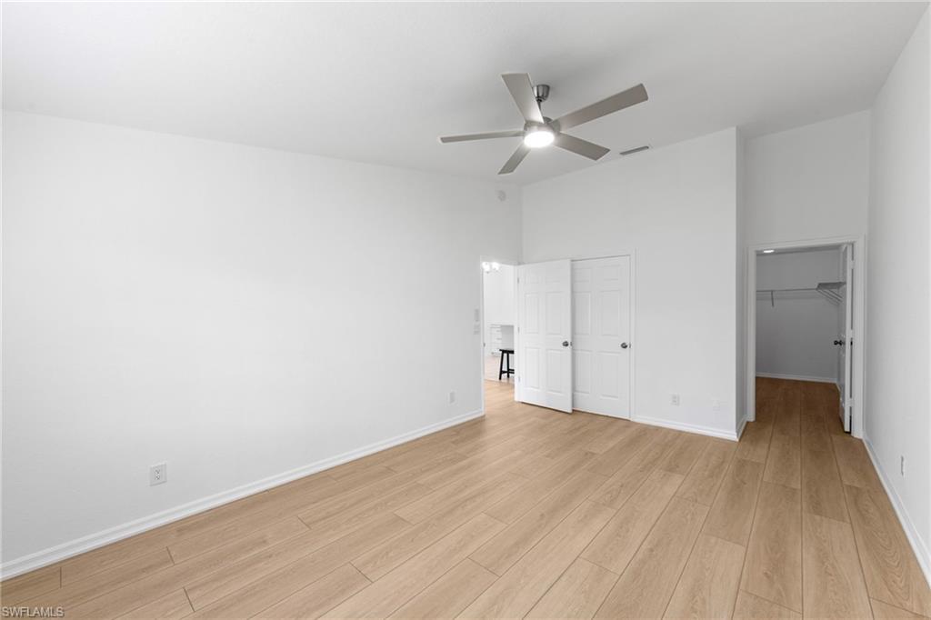 Spacious room featuring wood-finish flooring, white baseboards, and a contemporary ceiling fan with integrated lighting