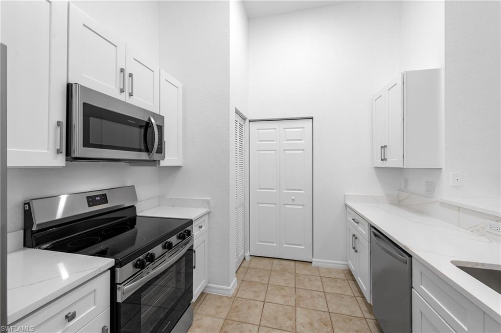 Bright kitchen featuring white shaker cabinetry, stainless steel appliances, light countertops, a tile backsplash, and tile flooring