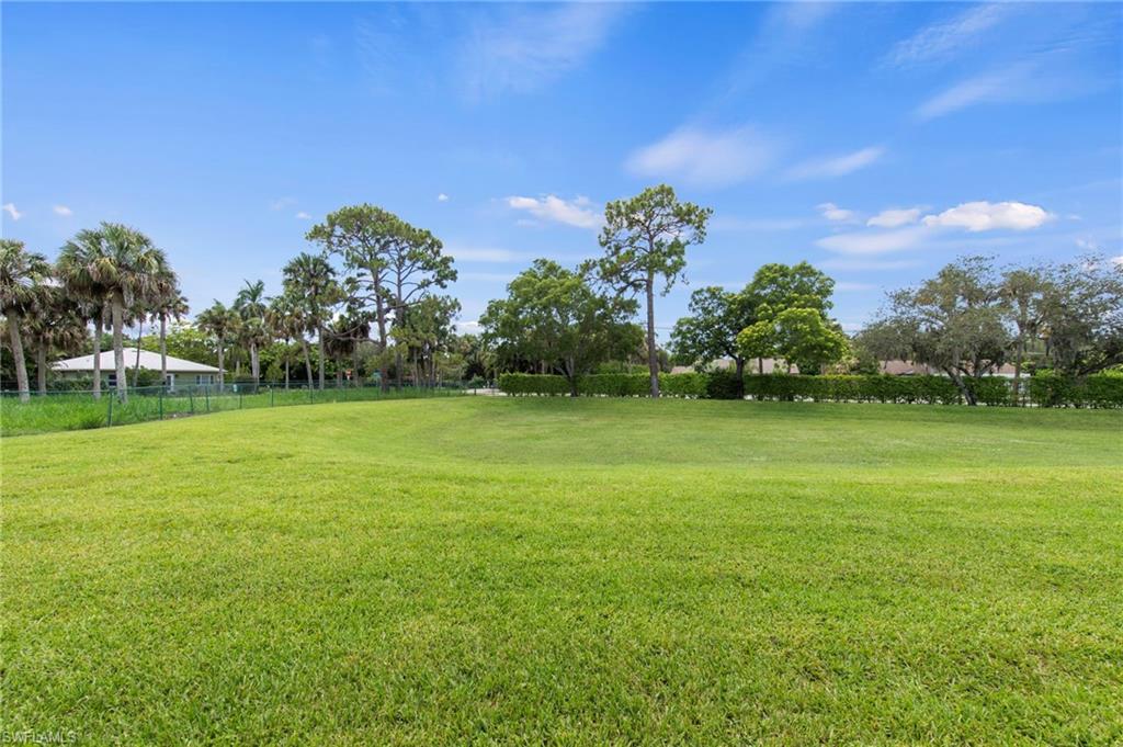 Expansive green lawn with mature trees and perimeter fencing
