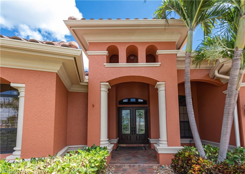 Entryway featuring a double-door entrance with decorative glass, arched portico, and architectural columns