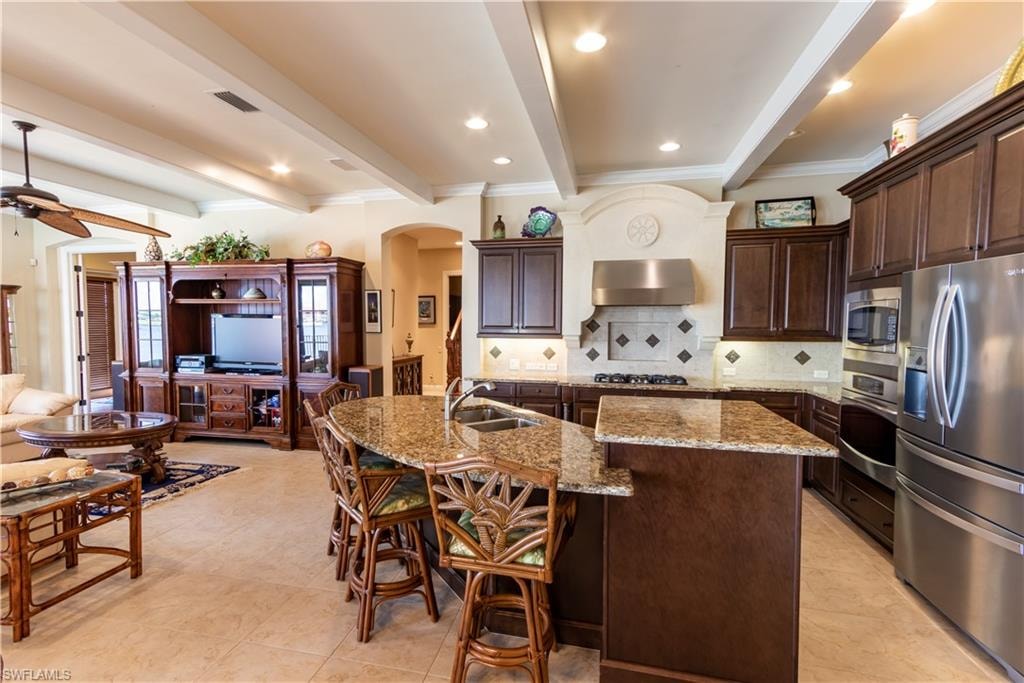 Kitchen featuring a curved island with stone countertops, dark wood cabinetry, and stainless steel appliances