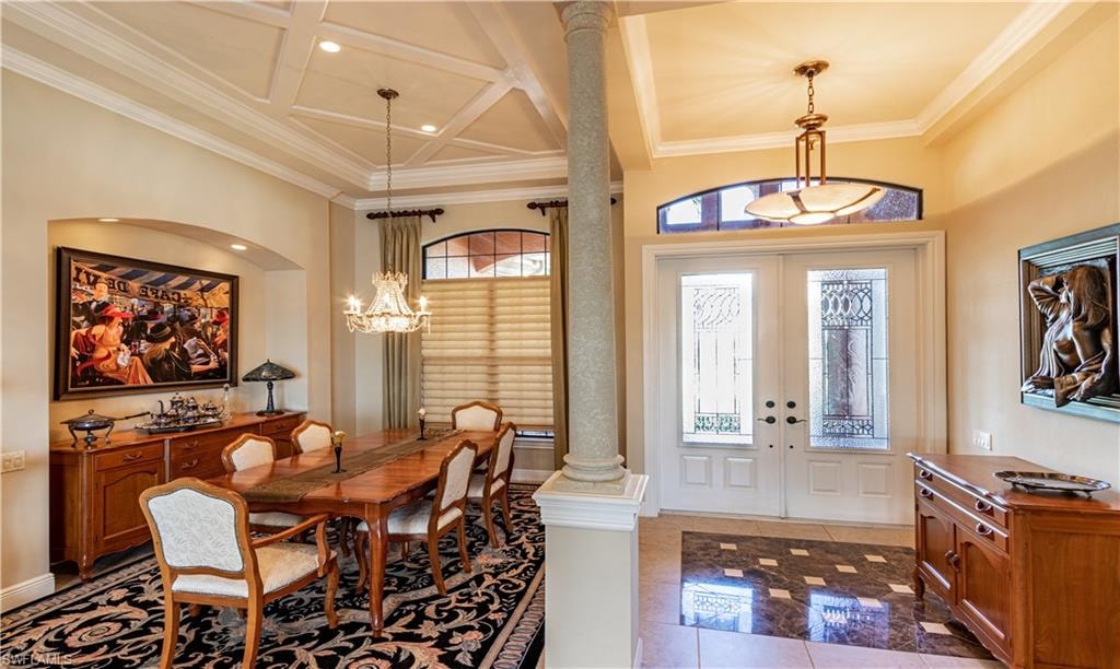 Foyer featuring double entry doors with decorative glass panels and an arched transom window, opening into an interior with a coffered ceiling, recessed lighting, and a decorative column