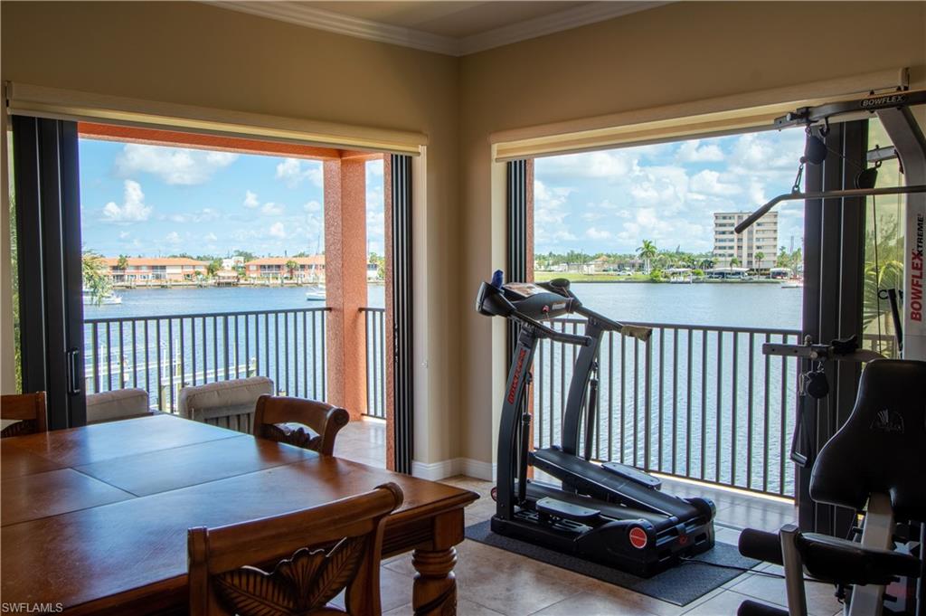 Expansive room featuring multiple full-height windows and glass doors opening to a waterfront balcony