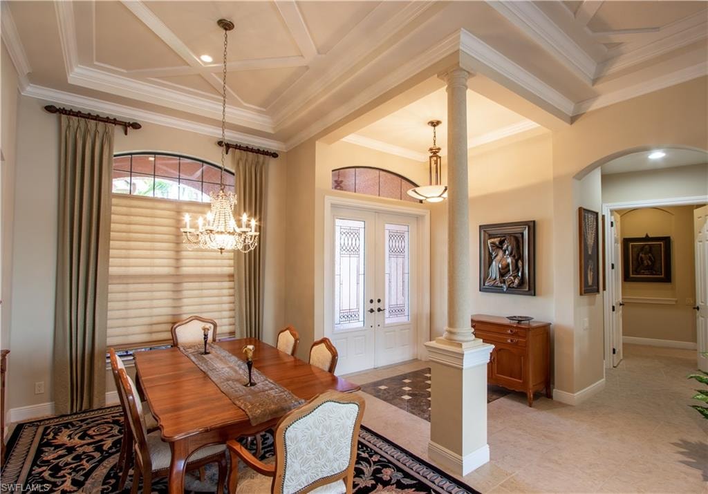 Formal dining area featuring a tray ceiling with crown molding, elegant chandelier, and arched window