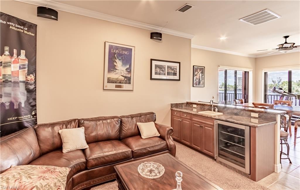 Open-concept living area featuring crown molding, recessed lighting, a built-in wet bar with a beverage cooler, and access to an outdoor balcony
