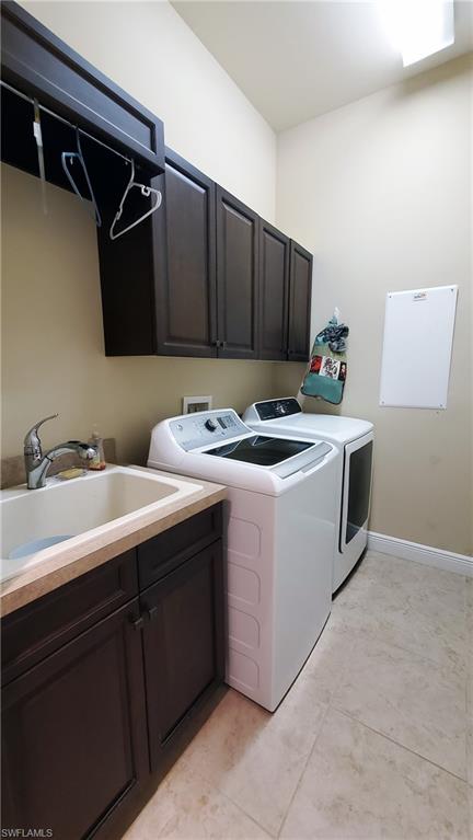 Laundry room featuring dark wood-finish cabinetry, a utility sink with a light-colored countertop, and tiled flooring