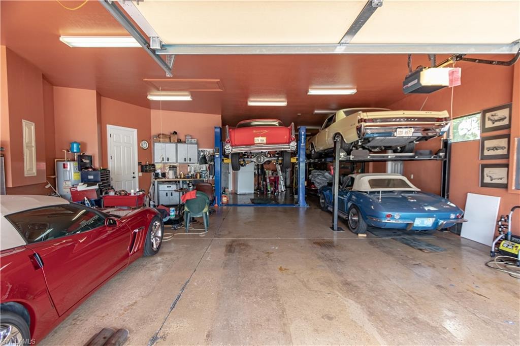 Spacious multi-car garage featuring a concrete floor, built-in storage cabinets, a car lift system, and overhead lighting