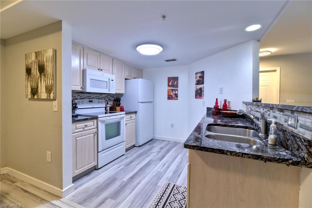 Kitchen featuring sink, backsplash, white appliances, and kitchen peninsula
